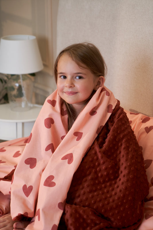 Pink baby blanket with red heart pattern, soft minky fabric, folded side view