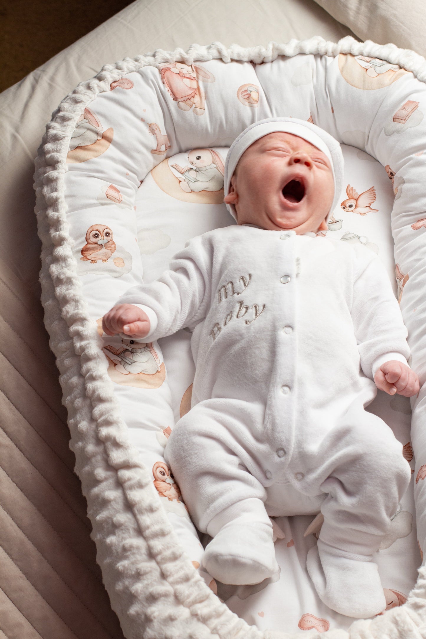 Baby cocoon nest with a soft Minky border, featuring a newborn baby lying comfortably inside