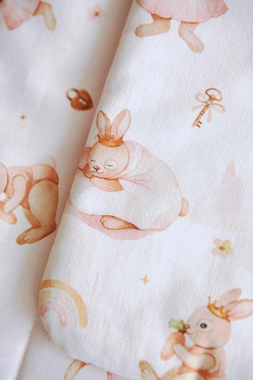 Fabric with pink bunny illustrations and a small branch in the corner