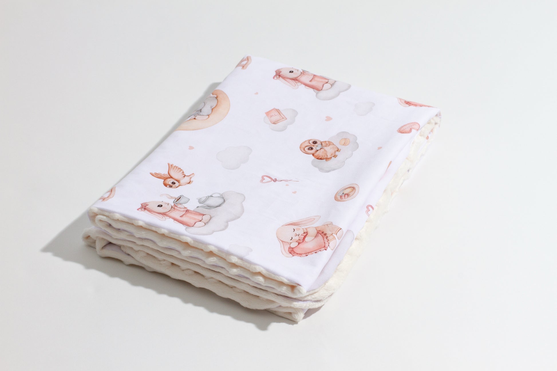 Folded baby blanket with Moony Dream print, made from Minky and cotton, showcasing bunnies and soft pastel clouds on a white surface.