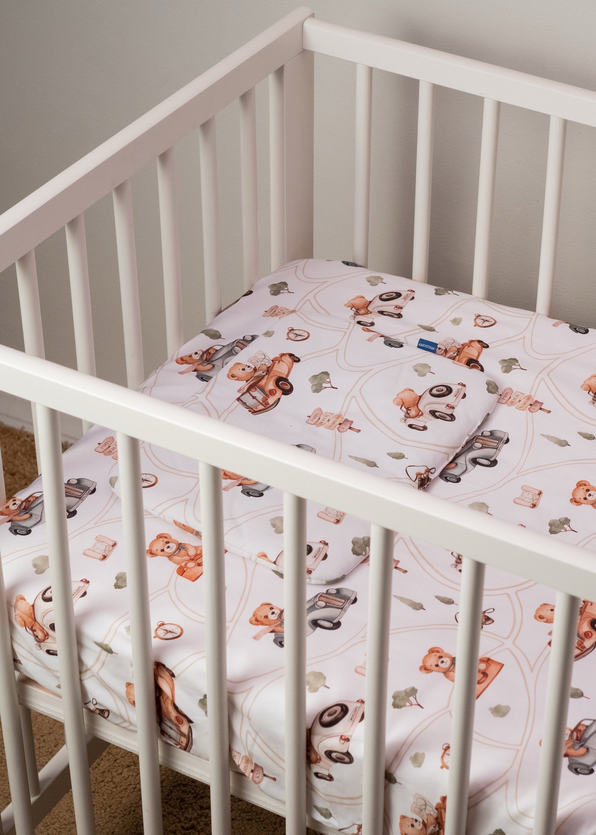 A baby crib with soft baby bedding featuring an adorable teddy bear design, providing a cozy and safe sleep environment