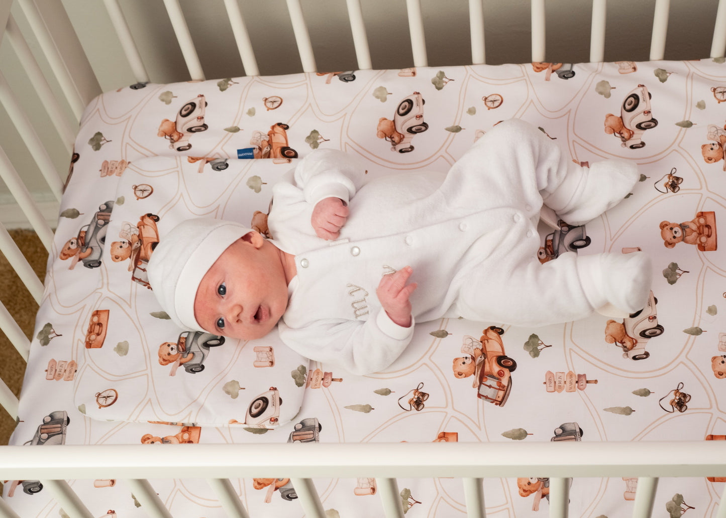 A newborn baby resting on a baby bedding set with a teddy bear design, capturing a peaceful and tender moment