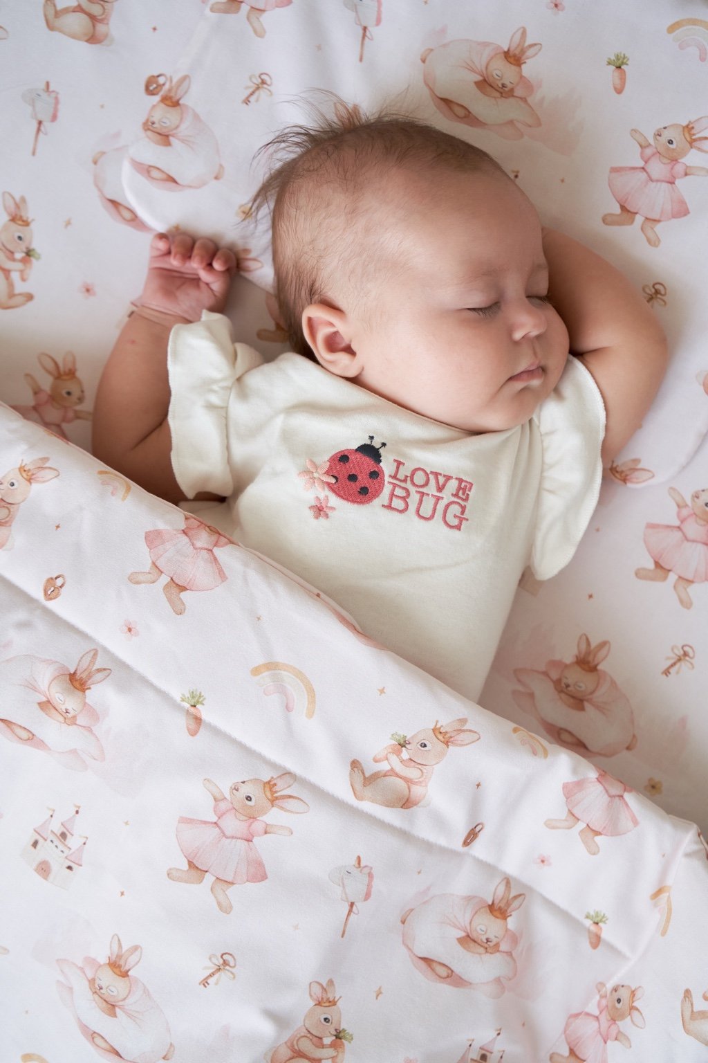 Baby sleeping peacefully on a children’s orthopedic pillow, complemented by a soft baby blanket in a crib