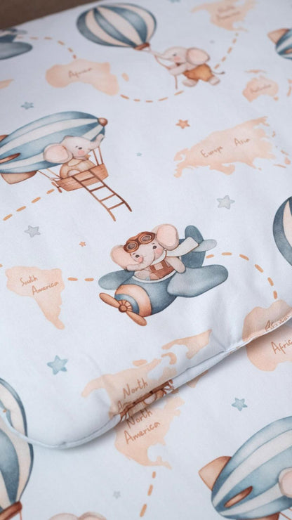 Close-up of a baby pillow with a charming hot air balloon and airplane print on a soft light blue fabric, perfect for adding comfort and style to a child’s crib