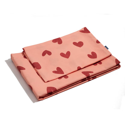 A folded Heartland pink bedding set with heart patterns, made from premium cotton for a soft and luxurious feel